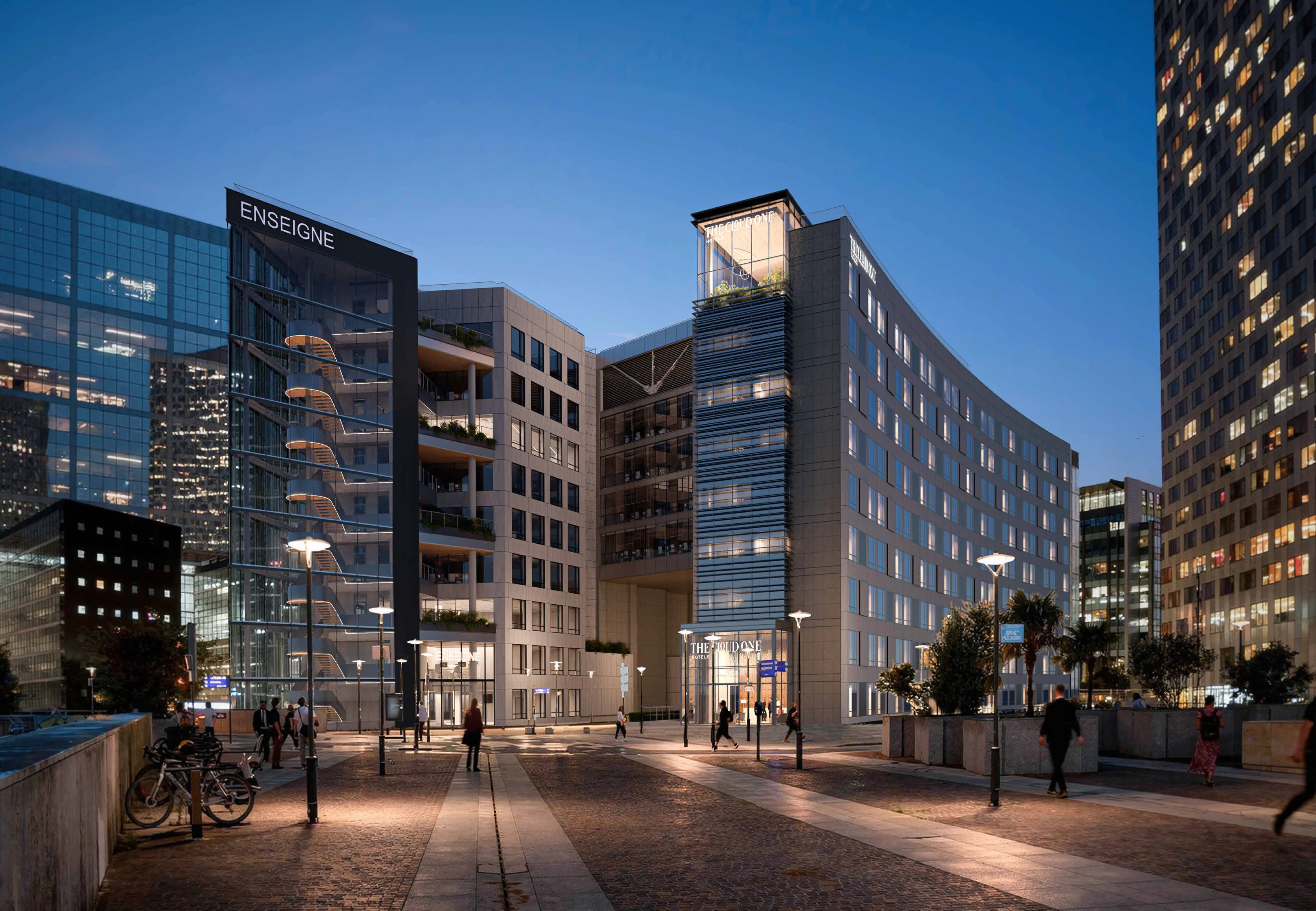 Le Triangle de l’Arche à la tombée du jour, depuis l’allée de l’Arche : les façades éclairées, le parvis et les tours de La Défense.